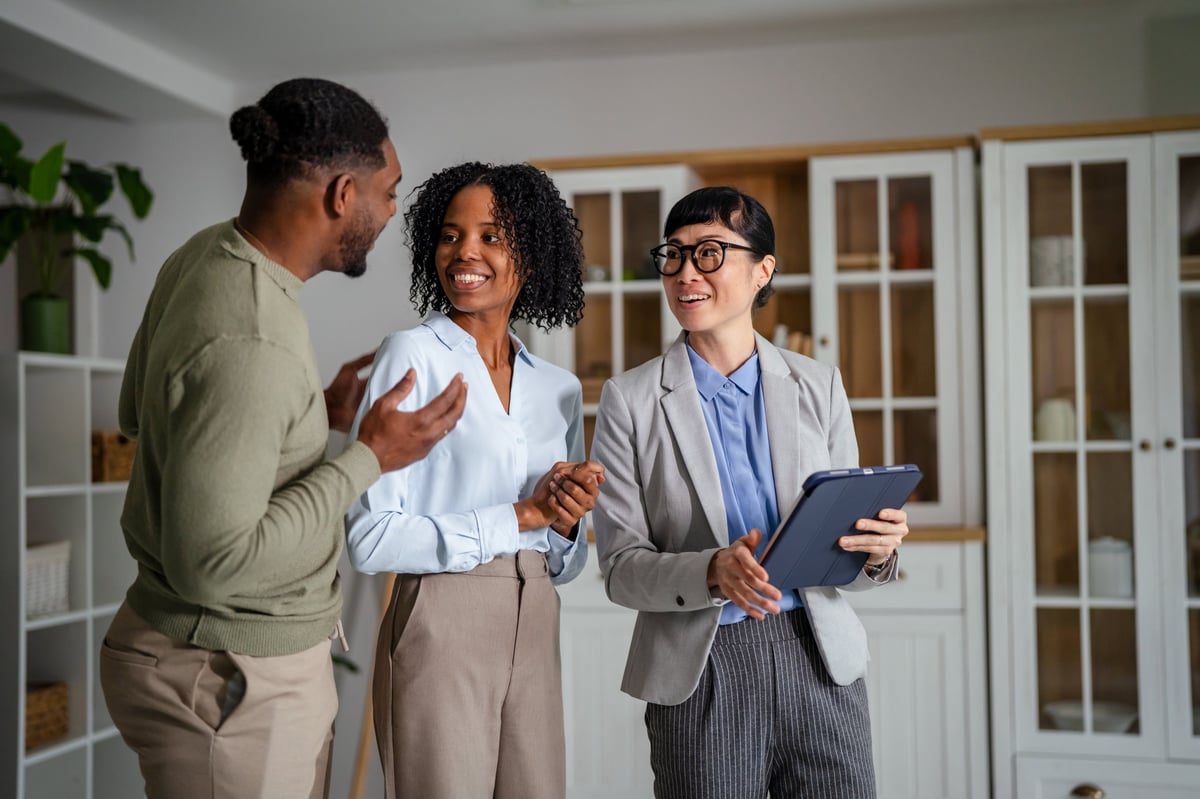Real estate agent showing property options on a tablet to a couple buying a home