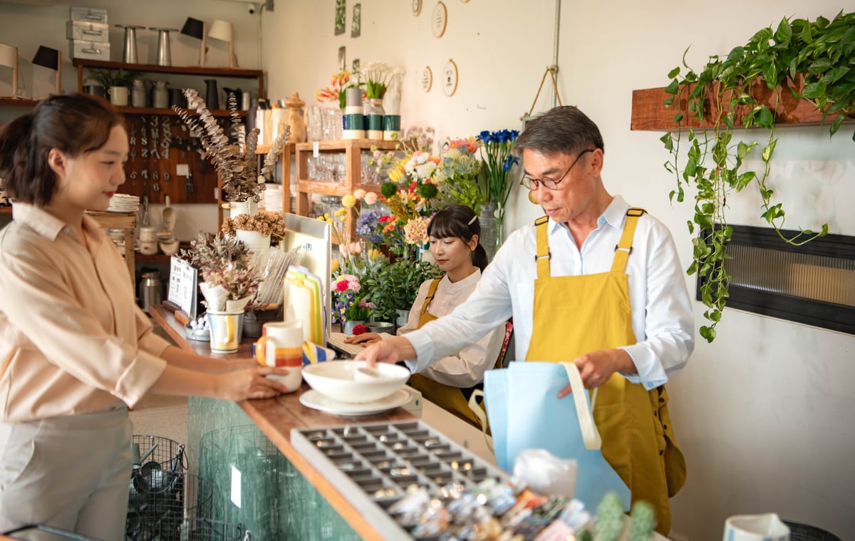 A small business owner serving a customer in their local shop